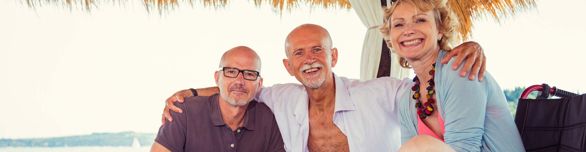 Woman in wheelchair and two men sitting at a beachside cafe